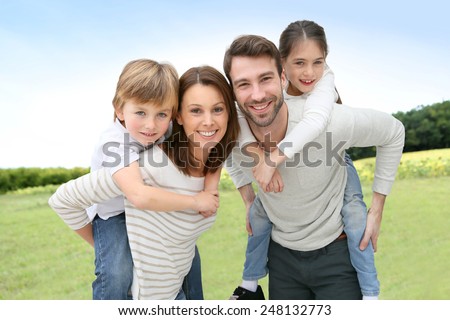 Young parents giving piggyback ride to kids