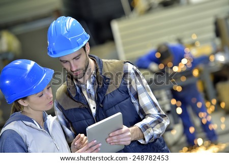 Engineers in steel factory working on digital tablet
