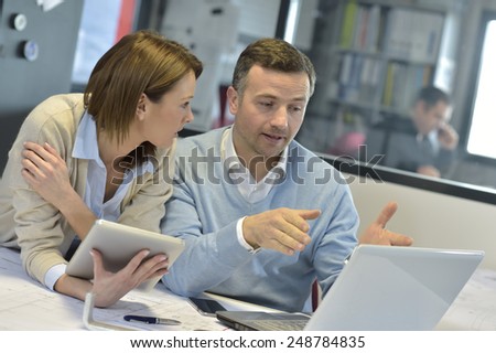 Business people in office working on laptop and tablet