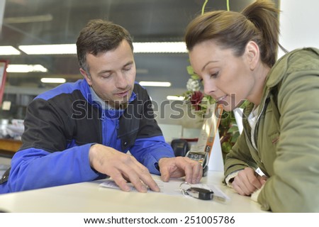 Mechanic showing repair bill to car owner