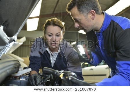 Mechanics instructor teaching woman in apprenticeship