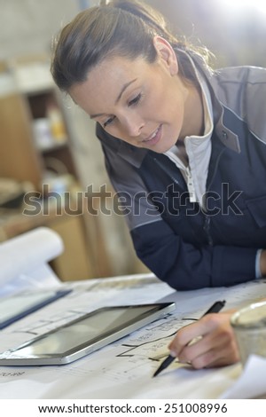Young woman carpenter designing plans in workshop