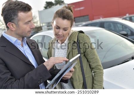 Car dealer showing car specifications to client on tablet