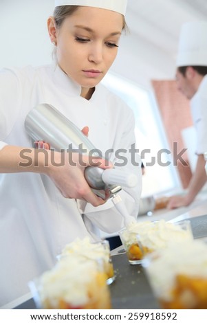 Pastry cook spreading whipped cream on dessert