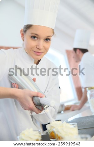 Pastry cook spreading whipped cream on dessert