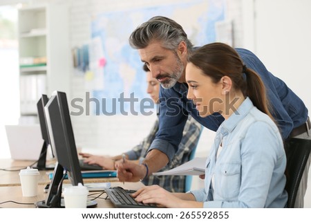 Trainer with student working on desktop computer