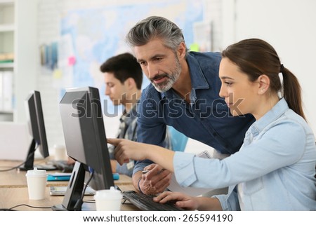 Trainer with student working on desktop computer