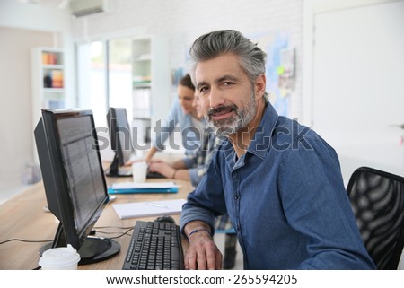 Smiling teacher working on desktop computer