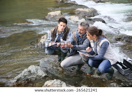 Biologist with students in science testing river water