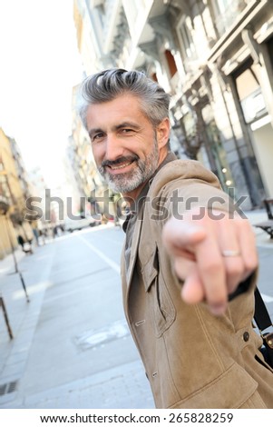 Handsome middle-aged man pointing finger at camera