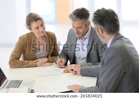 Mature couple signing financial contract at the bank