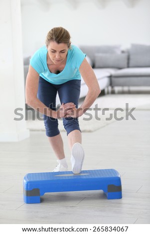 Middle-aged woman doing stretching exercises at home