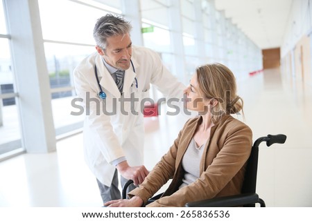 Doctor talking to woman in wheelchair after surgery