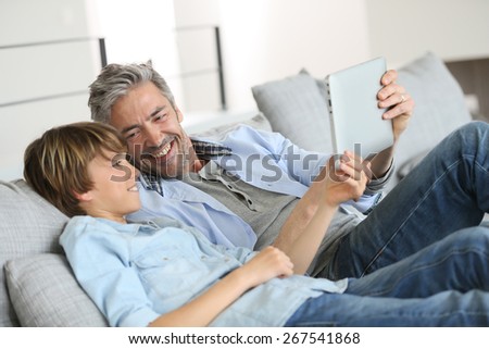 Daddy and son websurfing on digital tablet at home