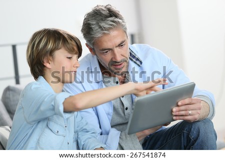 Daddy and son websurfing on digital tablet at home