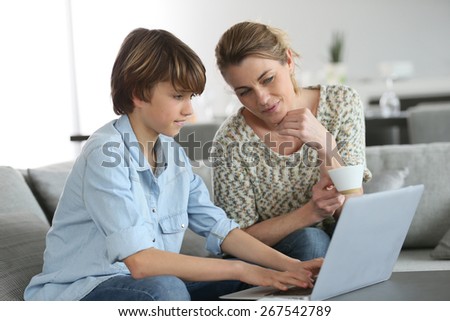 Mother looking after son doing homework on laptop