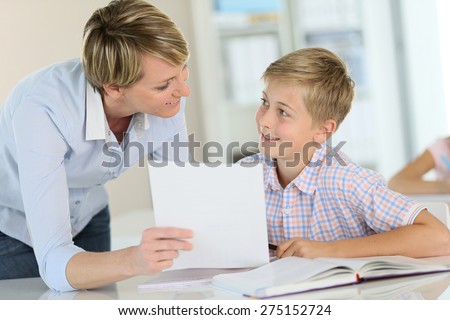 Teacher showing paper to pupil in class