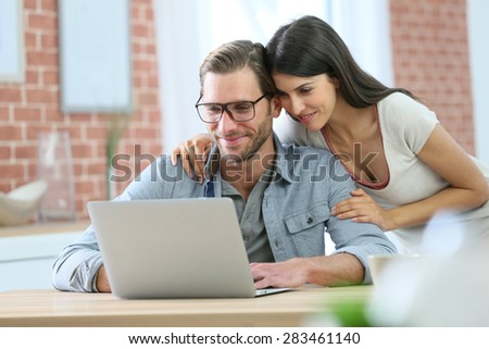 Couple at home websurfing on laptop computer