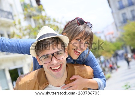 Man giving piggyback ride to girlfriend in the street