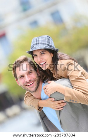 Young man giving piggyback ride to girlfriend in town
