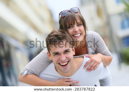 Young man giving piggyback ride to girlfriend in town