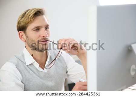 Businessman with eyeglasses sitting in front of desktop computer screen