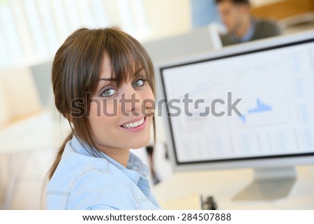 Portrait of cheerful office worker sitting in front of desktop