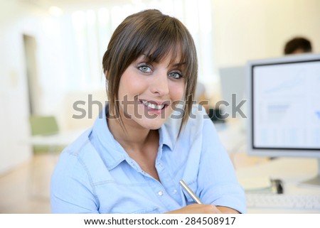 Portrait of cheerful office worker sitting in front of desktop