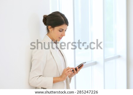 executive woman using smartphone in hallway