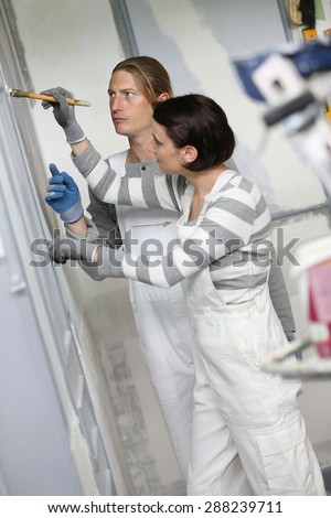 Young woman painter in professional training, teacher controlling work