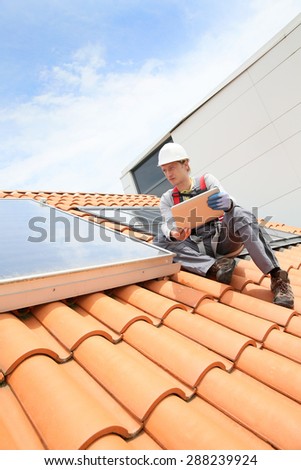 Man on roof top checking on solar panel installation