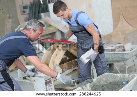 Teenager with professional brick layer in training school