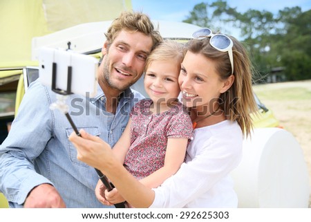 Family standing in front of camper van taking selfie picture