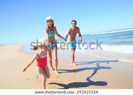 Family having fun running on a sandy beach