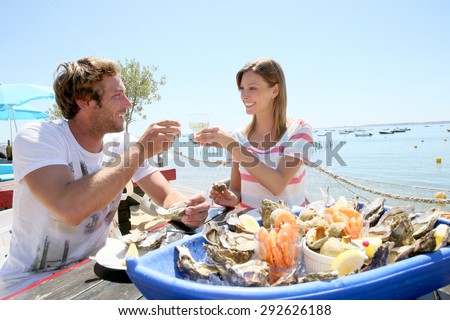 Couple in seafood restaurant tasting fresh oysters