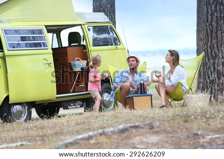 happy family relaxing by camper van in summer