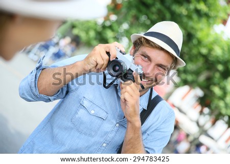 Trendy guy with hat taking picture of woman with vintage camera