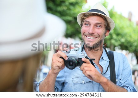 Trendy guy with hat taking picture of woman with vintage camera