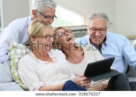 Group of senior friends with eyeglasses using digital tablet