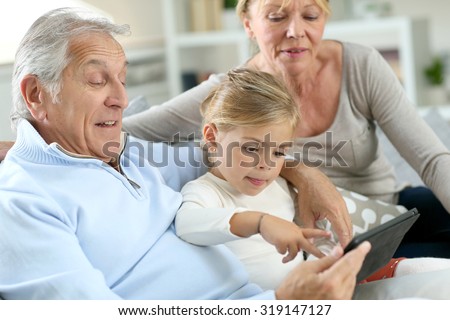 Grandparents with little girl using digital tablet
