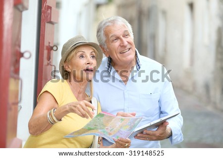 Senior tourists walking in street with map and tablet