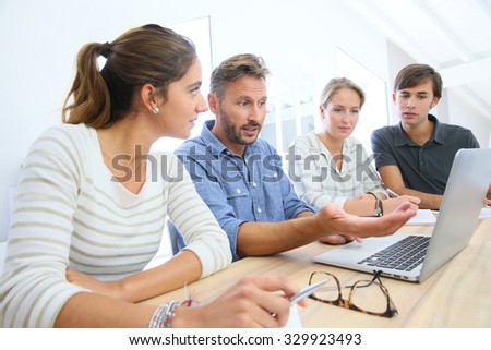 Teacher with group of students working on laptop computer