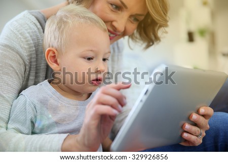 Mother and baby son playing with digital tablet