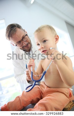 Baby boy at doctor\'s office playing with stethoscope