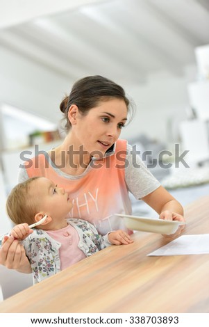 Busy mother on the phone feeding baby a the same time