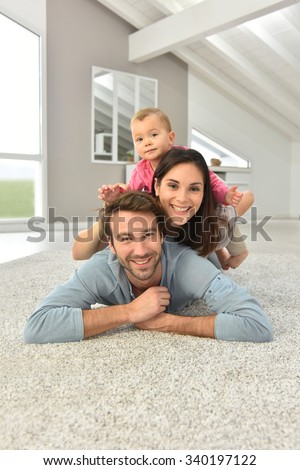 Parents and baby girl laying on carpet,