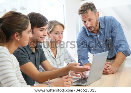 Teacher with group of students working on laptop computer
