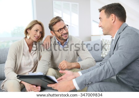 Couple with realtor signing mortgage contract