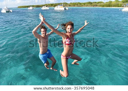 Cheerful couple jumping into water from boat