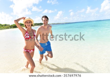 Cheerful couple running on a white sandy beach